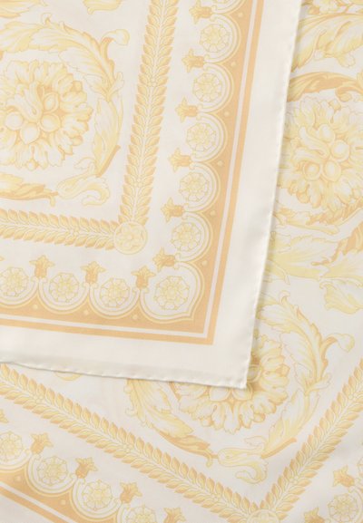 Μεταξωτό μαντήλι με κρεμ φόντο και περίπλοκα κίτρινα ανθικά και φυλλώδη σχέδια, με περίμετρο διακοσμητική κίτρινη κορδέλα.