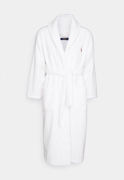 Biały szlafrok wykonany z miękkiego, pluszowego materiału. Posiada kołnierz szalowy, dwie przednie kieszenie, pasek do wiązania oraz haftowane logo na piersi.