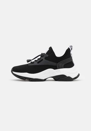 Black and white low-top sneaker with knitted upper, elastic bungee laces, textured sole, and pull tab at heel on a white background.