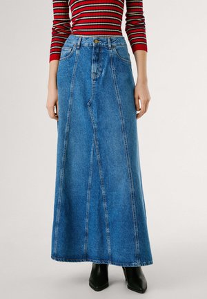 Lang denimskjørt i lyseblått med bred silhuett, definerte sømmer og frontlommer. Brukt sammen med en stripete topp i rødt og svart og svarte støvler.