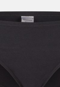 Zwarte katoenen bikini slip met een gladde textuur, voorzien van een zachte tailleband en een genaaid etiket. Geen zichtbare patronen of accenten.
