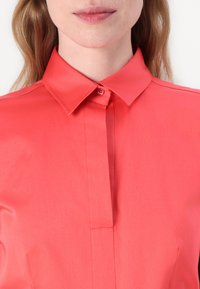 Coral shirt with a classic collar, front button closure, and smooth fabric texture. Slim fit with a neat placket.