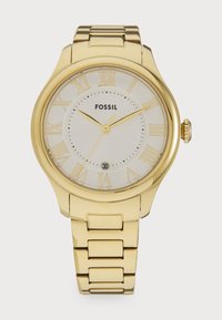 Montre en acier inoxydable doré avec un cadran blanc, des chiffres romains, un affichage de la date et un bracelet à maillons poli. Logo marqué au centre.