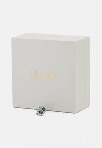 Liu Jo earring box features a sleek, gray exterior with gold branding. Two green stone earrings are displayed in front.