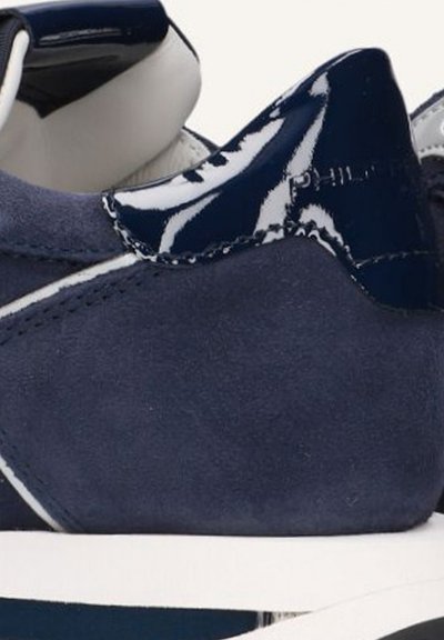 Baskets en daim bleu marine avec un accent en cuir verni brillant au talon, couture blanche et semelle en caoutchouc blanche.