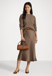 Brun strikkegenser, beige satengskjørt, brun lærbelte og matchende håndveske. Brune lukkede pumps. Glatte teksturer, minimal detaljering.