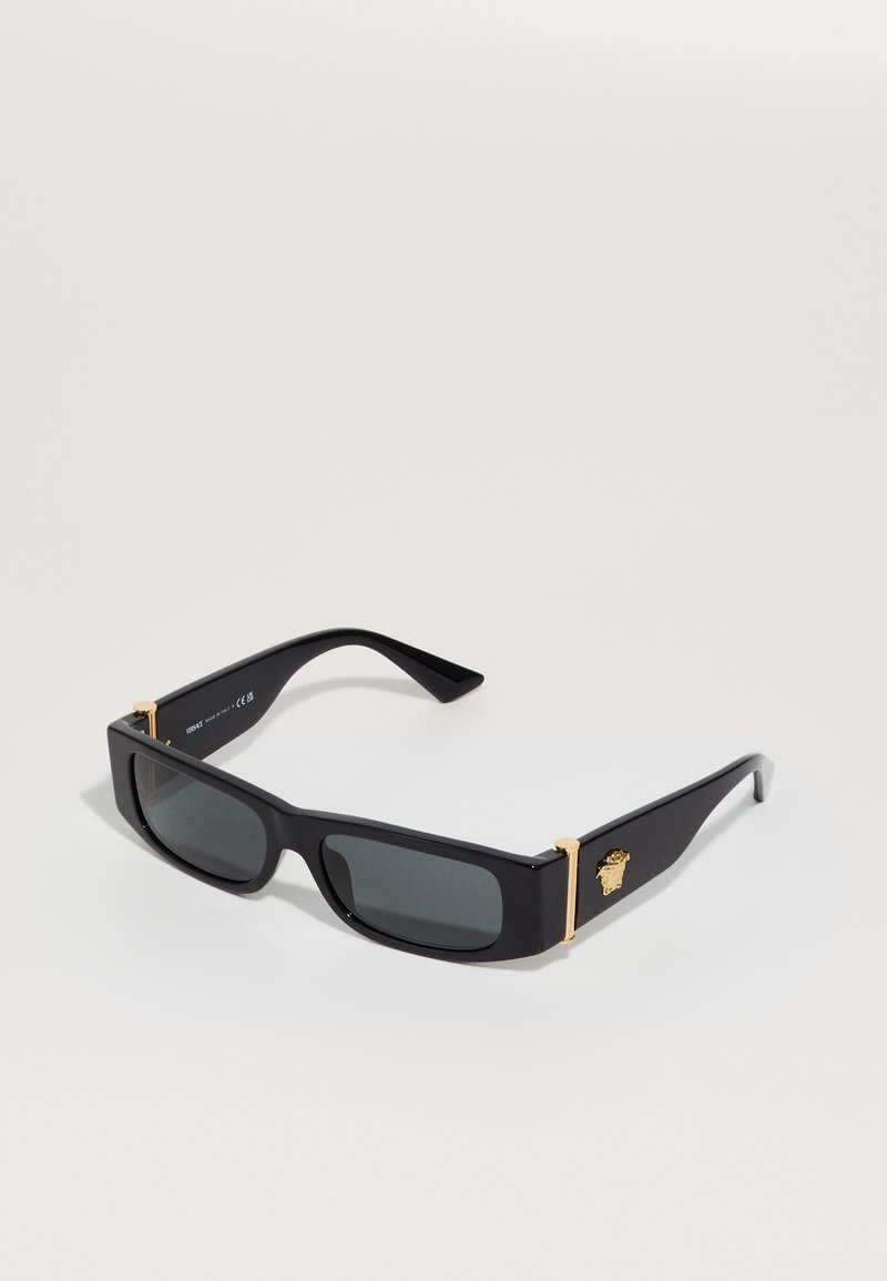 Black rectangular sunglasses with dark lenses. Features gold-tone accents on the arms with logo detail. Made of plastic, sleek design.