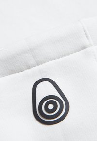 Tela blanca con un acabado texturizado presenta un destacado logo abstracto negro que asemeja una forma de lágrima con círculos concéntricos.