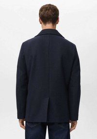 Abrigo azul marino de mezcla de lana con cuello de solapa, abertura trasera única y dos bolsillos laterales. Corte estructurado, textura suave, detalles mínimos en la parte trasera.