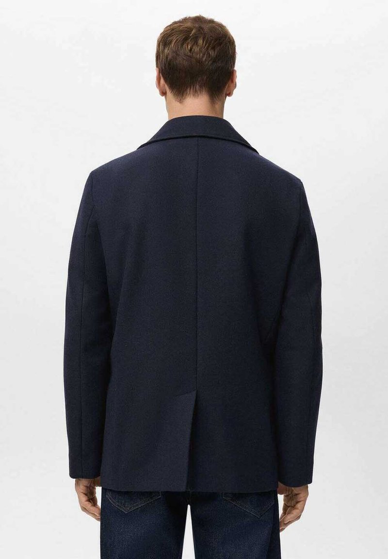 Marineblauer Mantel aus Wollmischung mit Reverskragen, Einzelventil und zwei Seitentaschen. Strukturierte Passform, glatte Textur, minimalistische Details auf der Rückseite.