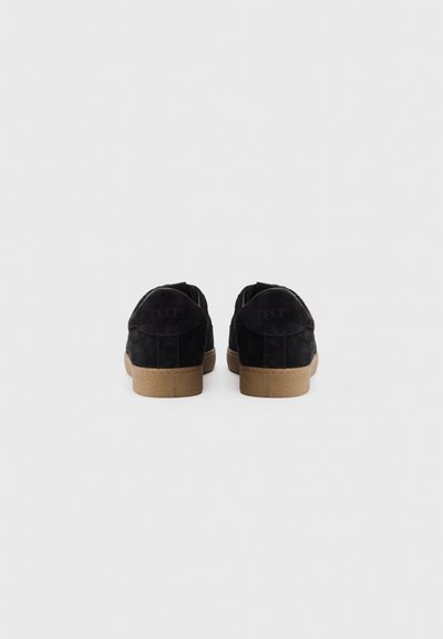 Black suede sneakers with a textured finish, rubber soles, and subtle branding on the heel; designed for casual wear and comfort.
