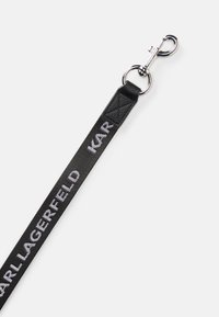 Black fabric strap with white "KARL LAGERFELD" text and silver metal lobster clasp on a plain white background.