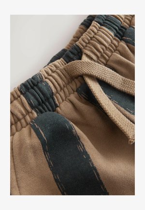 Ruda ir tamsiai žaliai dryžuotos elastingos juosmens šortai su tekstūruotu raišteliu ir surinkta audiniu, demonstruojantys kasdienį dizainą.