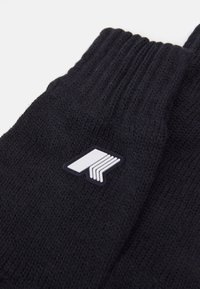 Guanti neri a maglia con polsini a coste, dotati di una toppa con logo bianco caratterizzata da un design geometrico. La textura appare morbida e calda.
