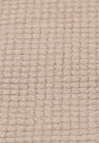 Beige ulltyg med ett texturerat rutmönster, mjuk, filtliknande yta, jämnt vävd med upphöjda rutor genom hela.