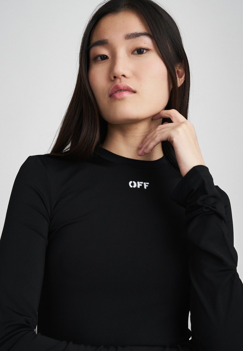 Top negru cu mâneci lungi, din material moale, având un decolteu rotund și logo-ul „OFF” în alb pe piept. Design ajustat cu mâneci rézervate.