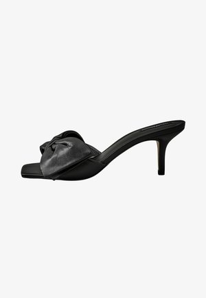 Black leather heeled mules with a knot detail on the upper strap and a smooth finish. Square toe and slim stiletto heel.
