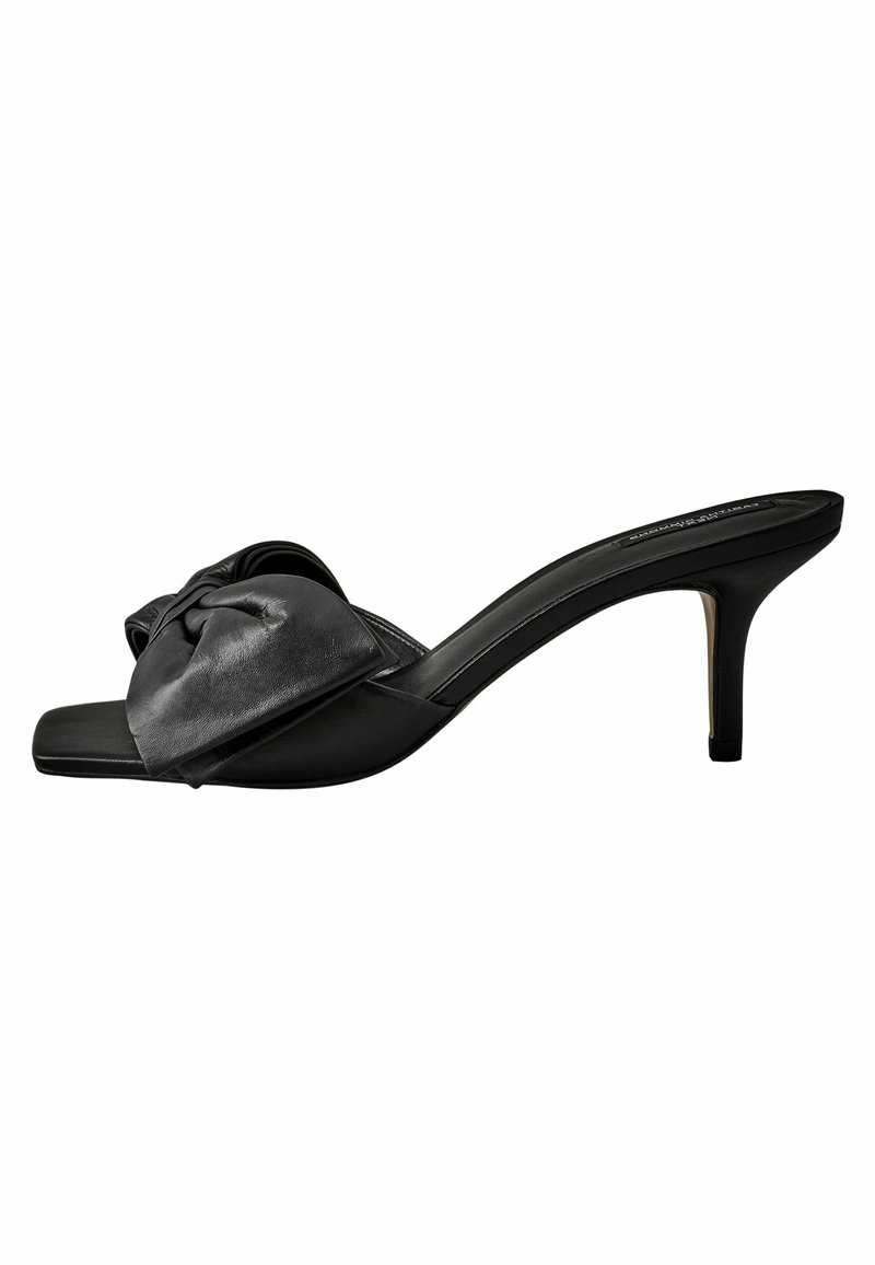 Mules à talons en cuir noir avec un détail de nœud sur la lanière supérieure et une finition lisse. Bout carré et talon aigu slim.
