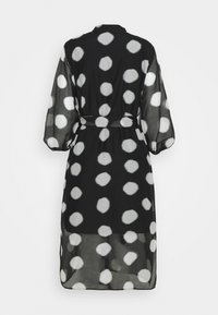 Robe noire transparente à grands pois blancs, manches longues bouffantes, taille ceinturée et longueur midi, vue de dos.