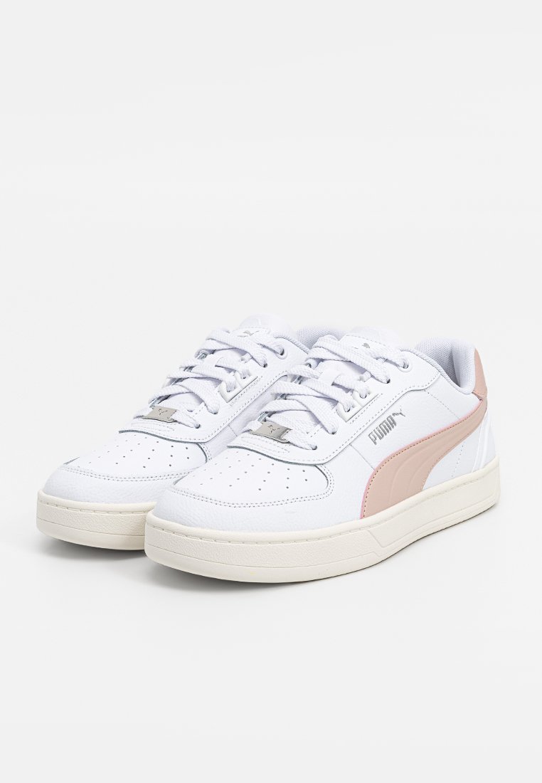 Baskets blanches avec une tige en cuir texturé, des accents roses sur le côté, des détails perforés sur l'orteil et une semelle en caoutchouc légère.