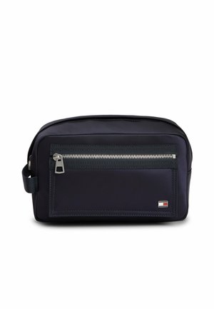 Compact black toiletry bag with front zip pocket, side handle, and small rectangular logo in red, white, and blue on lower right corner.