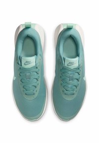 Ljusblå Nike-sneakers med mesh-övre, rund tå, texturerade snören och en vit sula. Har en logotyp på tungan och en bakre dragflik.