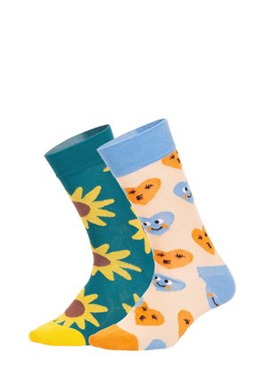 To par bomuldsokker: et par grønne med gule solsikker og et par ferskenfarvede med blå og orange hjerte-motiver. Hvert par har kontrastfarvede kanter.