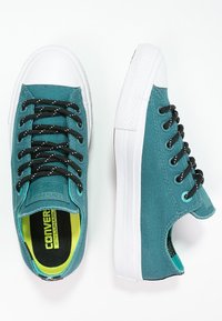 Baskets en toile bleu sarcelle avec œillets et lacets noirs, semelles en caoutchouc blanches et semelles intérieures jaunes. Présentent un tissu texturé et un design à bout arrondi.