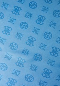 Tissu bleu clair présentant un motif répétitif de motifs circulaires et floraux en bleu plus foncé, créant une apparence texturée et superposée.