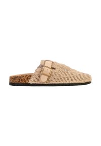 Mule beige en crochet à enfiler avec une semelle en liège, un dessous noir, et une bride en cuir ajustable avec une boucle dorée sur le côté.