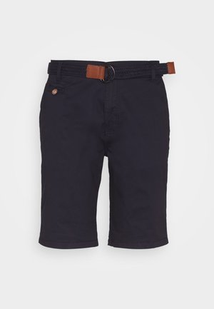 Marineblauwe kniebrede shorts met een gevlochten riem met bruine leren accenten en een kleine knoopzak aan de rechterkant.