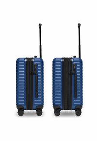 Due valigie rigide blu con dettagli neri, design a righe verticali, serratura a combinazione integrata e quattro ruote per un facile spostamento.