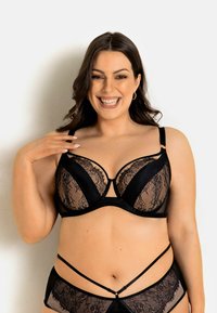 Czarny koronkowy biustonosz z półprzezroczystymi miseczkami, wsparciem w postaci fiszbin i regulowanymi ramiączkami. Wyjątkowy design obejmuje wycięcie na środku oraz koronkowe akcenty.