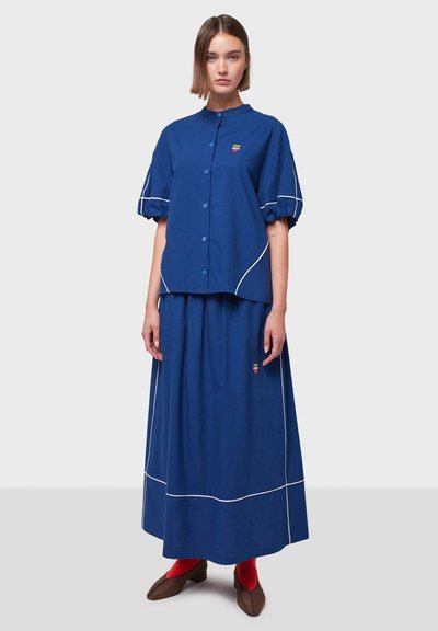 Conjunto de camisa y falda de algodón azul, con detalles en blanco, una camisa abotonada con cuello redondo y un sutil bordado.