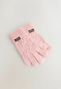 Lichtroze gebreide handschoenen met een geribde manchet, voorzien van een kabelbreipatroon en twee labels op de pols. Zachte textuur, warm ontwerp.