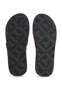 Sorte gummiflip-flopsåler med et tekstureret grebmønster. Røde accenter langs kanterne og en kontureret indersål for komfort.