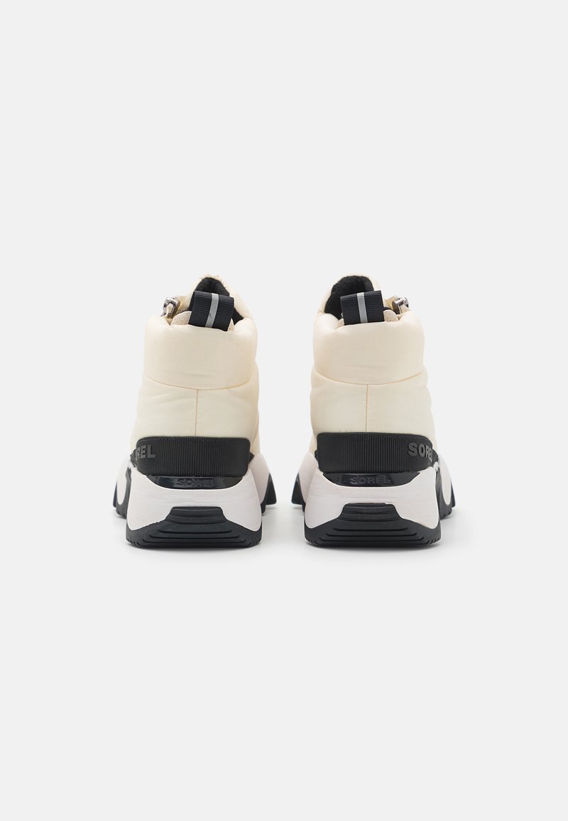 Ein Paar cremefarbene Winterstiefel mit schwarzen Sohlen und Ziehschlaufen, von hinten auf einem schlichten weißen Hintergrund betrachtet.