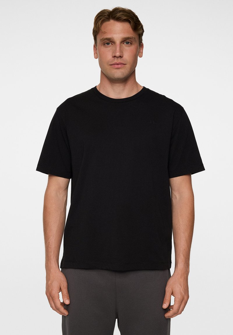 Mustat, lyhythihainen t-paita pehmeästä kankaasta, jossa on pyöreä kaula-aukko ja rento istuvuus. Ei näkyviä logoja tai kuvioita.