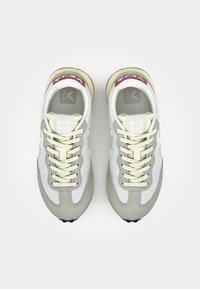Sneaker a rete grigie e bianche con accenti beige, dotate di una punta in camoscio testurizzato, lacci crema e una toppa con logo rosso e bianco sulla linguetta.