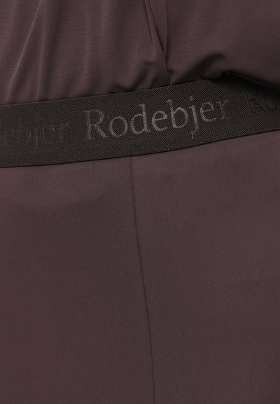 Mørk lilla plagg med en glatt tekstur, med et svart midjebånd preget med "Rodebjer" i et subtilt mønster.