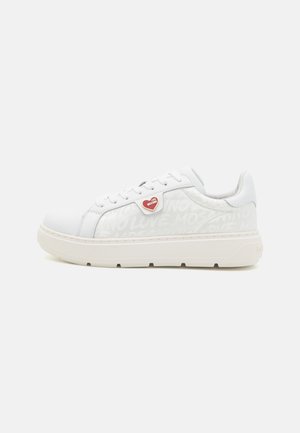 Zapatillas blancas con un upper texturizado que presenta un detalle de corazón y un patrón de "NO LOVE". Suela de goma gruesa con sutiles acentos beige.