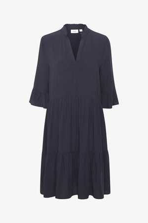 Tengerészeti kék ruha háromnegyedes ujjakkal, fodros mandzsettával, V-nyakkivágással és réteges szoknyával. Simább, könnyű anyagból készült.