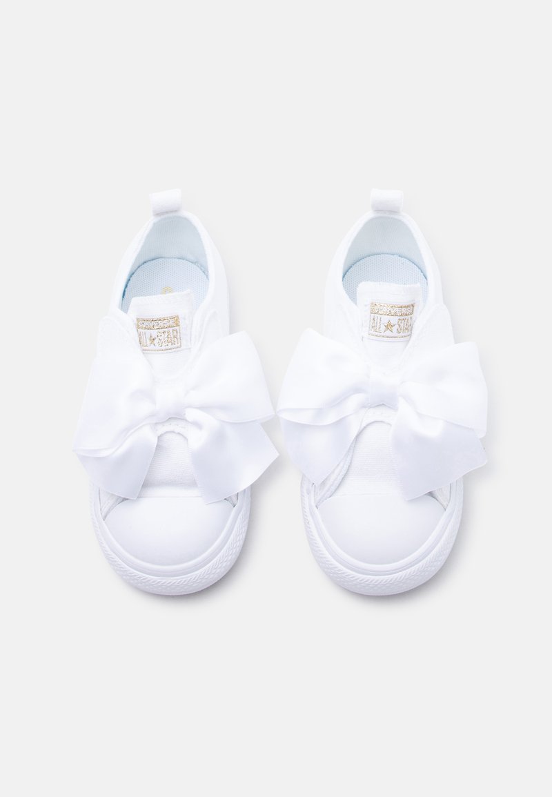 Λευκά παιδικά αθλητικά παπούτσια με μεγάλα σατέν φιόγκους στην κορυφή και υφασμένα λαστιχένια πέλματα, φωτογραφημένα από πάνω σε λευκό φόντο.
