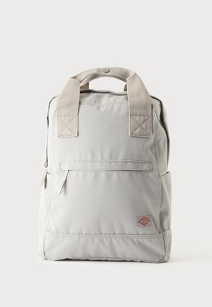Jasnoszary plecak z beżowymi materiałowymi uchwytami, przednią kieszenią na zamek i małą kolorową naszywką z logo Dickies w dolnym prawym rogu.