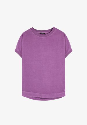 Fioletowa koszulka z krótkim rękawem, wykonana z bawełny, z okrągłym dekoltem i luźnym krojem z prostym dołem. Gładka faktura, bez wzorów.