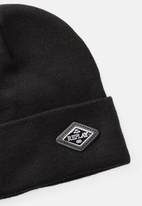 Căciulă tricotată neagr�ă cu textură cu nervuri, având o pătrat negru în formă de diamant cu logo-ul alb "REPLAY" și anul "1981".