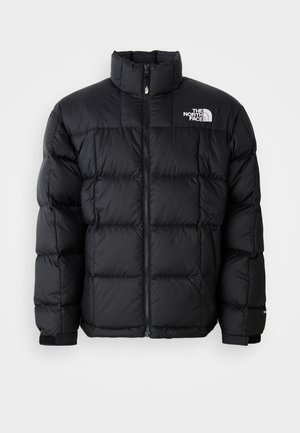 Casaco puffer preto com colarinho alto, costuras horizontais e fecho de zip. Apresenta o logotipo no lado superior esquerdo e punhos de velcro.