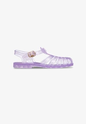 Sandale en gelée lavande transparente avec paillettes, bout fermé et arrondi, et une bride réglable à la cheville avec boucle.