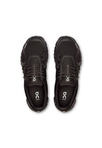 Schwarze Sportschuhe mit einem atmungsaktiven Mesh-Obermaterial, Gummisohle und minimalistischem Design. Schnürverschluss mit Logo auf der Innensohle.