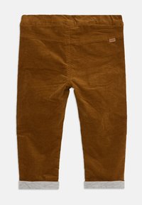 Bruna kordflamsbyxor med en mjuk textur, med grå frans och elastisk midja. En liten märkesetikett syns på baksidan.